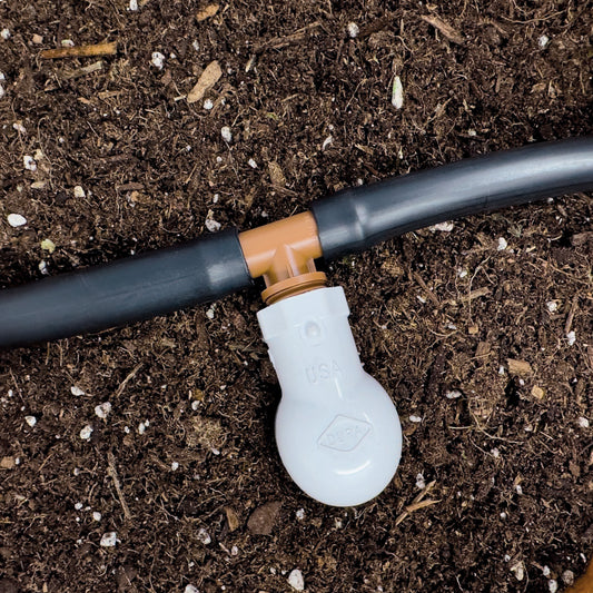 A brown barbed 1/2" drip tube adapter tee with a 1/2 inch male pipe thread (MPT) with soil in the background.