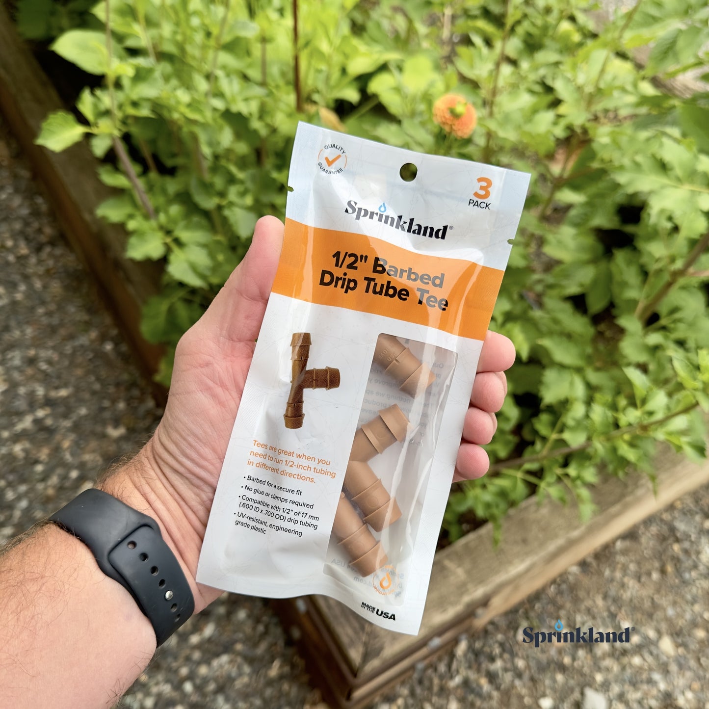 A 3 pack of brown 1/2" barbed drip tube tee fitting with plants and soil in the background.