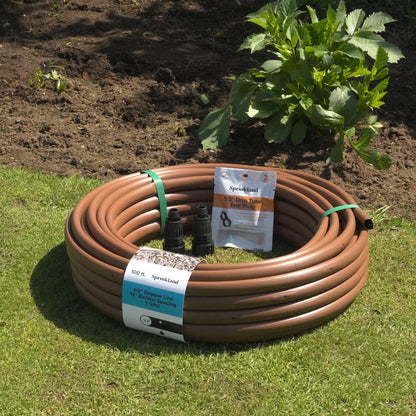 Coiled brown drip tubing with labels on a grassy area with plants in the background