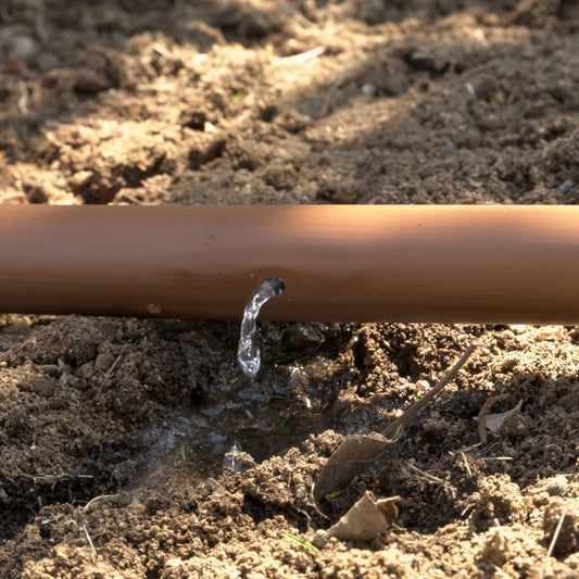 Drip irrigation pipe with water droplet on a soil background